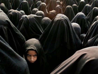 ISTANBUL, TURKEY - FEBRUARY 20: A Turkish girl stands in a crowd of women wearing burqas d