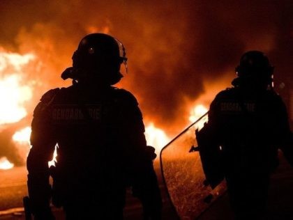 A vehicle burns as French riot police clear the Place de la Republique in Paris during a p