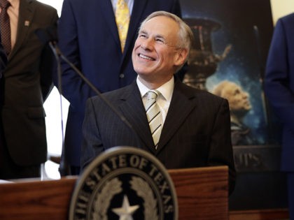 A poster with an image of Texas Gov. Greg Abbott is seen behind Abbott at a news conferenc