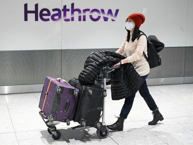 Passengers wear face masks as the push their luggage after arriving from a flight at Termi