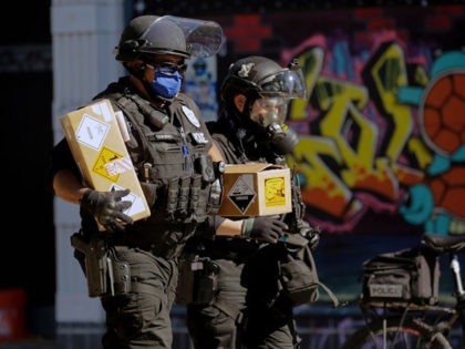 Seattle police officers carry boxes with warning stickers and a slip of paper that reads "
