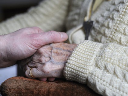In this file photo, a woman, suffering from Alzheimer's disease, holds the hand of a relat