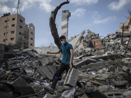 A Palestinian man inspects the damage of a six-story building which was destroyed by an ea