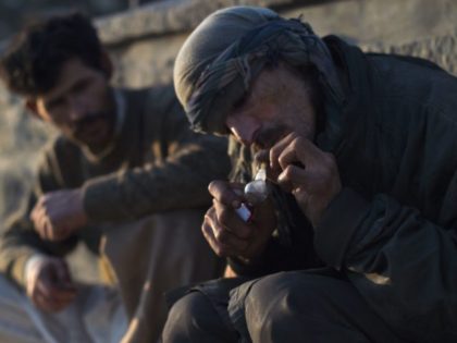 Addicts smoke opium along a roadside in Kabul on October 23, 2019. (Photo by WAKIL KOHSAR