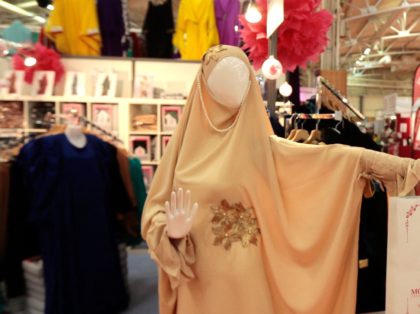 A Muslim woman passes next to a mannequin wearing a chador at the clothing stand in the co