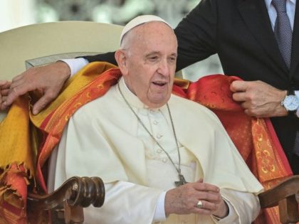 The Pope's assistant Sandro Mariotti (R) puts a shawl on Pope Francis' shoulders
