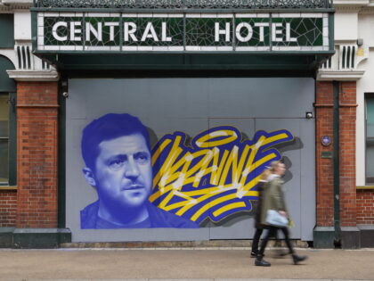 People pass a mural of President of Ukraine Volodymyr Zelenskyy, by the artist Aches, in c