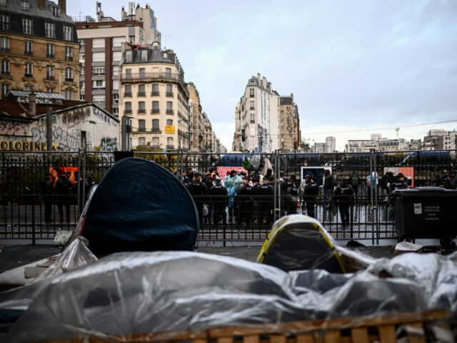 Cordoned by French Gendarmes mobile riot unit, migrants queue to embark buses for temporar