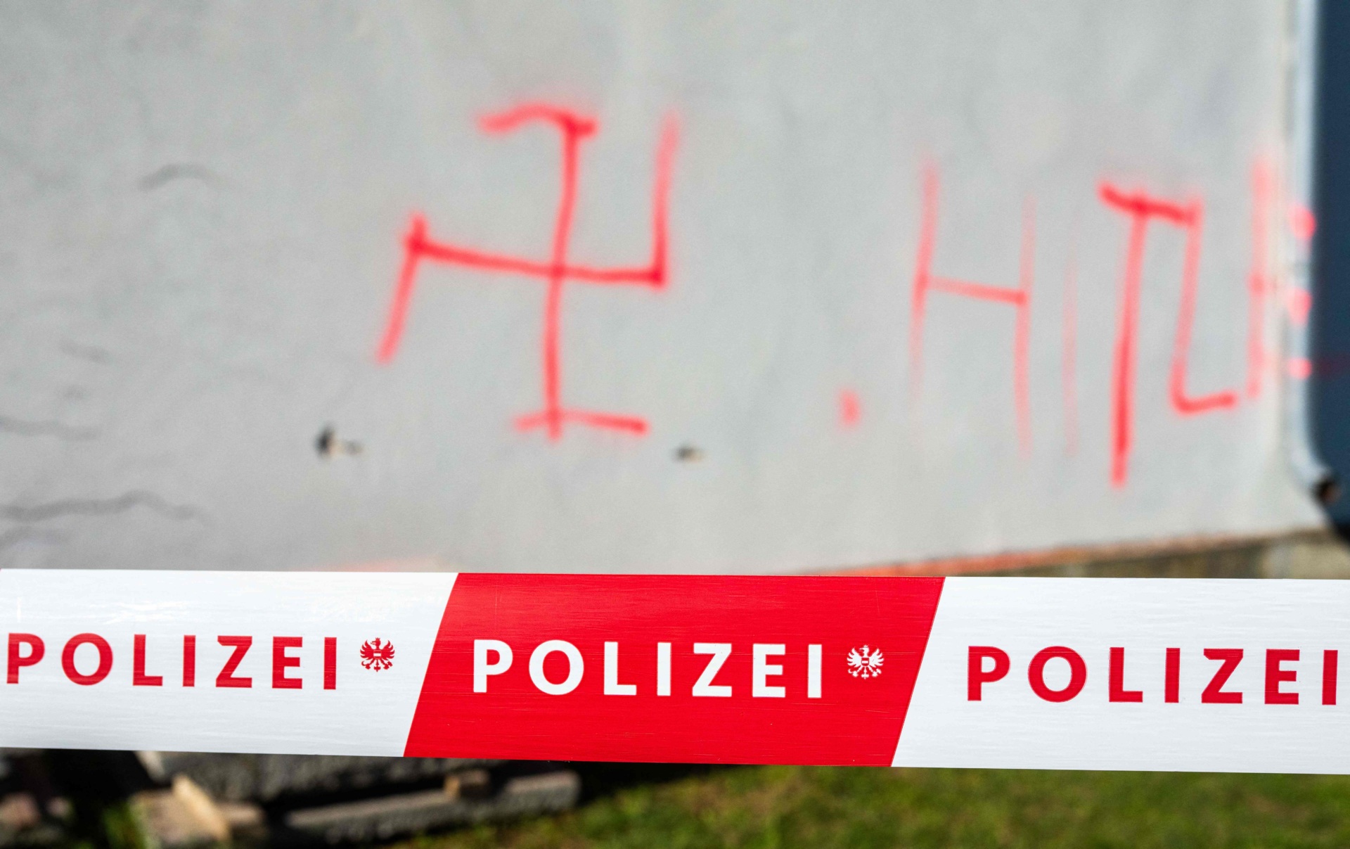 This photo taken on November 1, 2023 shows swastika symbols sprayed on an external wall in front of the ceremony hall at the Jewish part of the Central Cemetery in Vienna, Austria, after police cordoned off the area. Austrian police on November 1 were investigating a fire that damaged a hall at the Jewish part of the Vienna cemetery, with politicians condemning anti-Semitic violence. Cities in Europe have seen a spike in anti-Semitic attacks in response to the Israel-Hamas conflict. In the night from October 31 to November 1, a fire broke out at the Jewish part of the Vienna cemetery, damaging a ceremony hall, officers said. (Photo by GEORG HOCHMUTH / APA / AFP) / Austria OUT (Photo by GEORG HOCHMUTH/APA/AFP via Getty Images)
