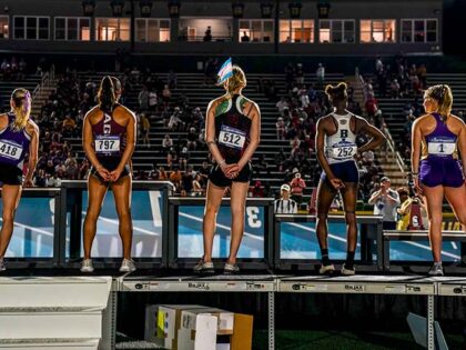 Sadie Schreiner, C, wears a transgender flag in her hair on the awards stand after finishi