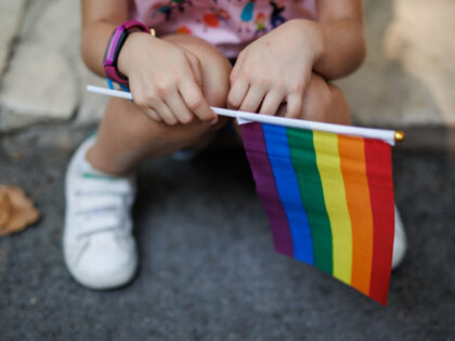 A girl holds the rainbow flag minutes before the start of a demonstration for LGTBIQ Pride