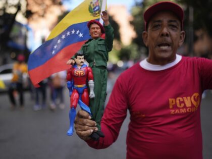 A government supporter holds action figures of late President Hugo Chavez and Super Bigote