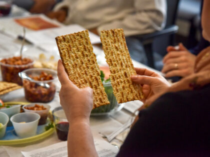 Rabbi Janet Ozur Bass breaks a piece of unleavened bread at an Interfaith Passover seder h