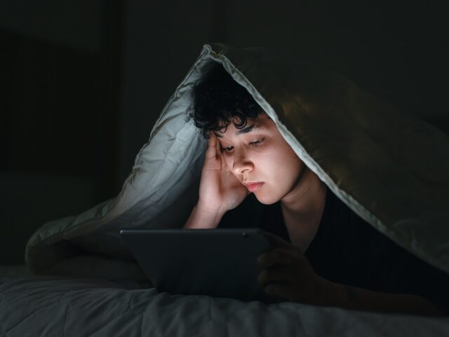 a boy using a tablet in bed